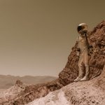 Astronauta em traje espacial sobre terreno rochoso semelhante à superfície de Marte.