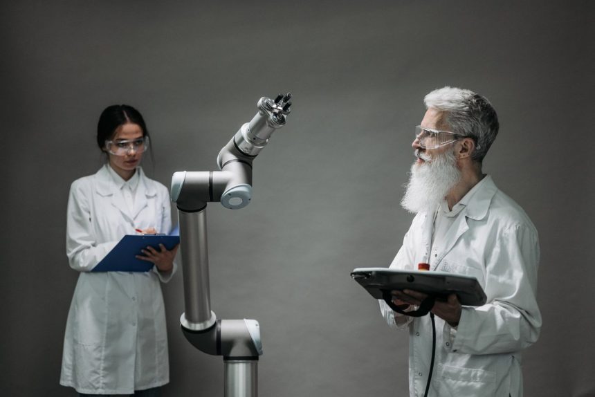 Dois pesquisadores trabalham juntos diante de um braço robótico em um laboratório de tecnologia.