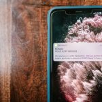 Celular exibindo um alerta de fraude sobre uma superfície de madeira.