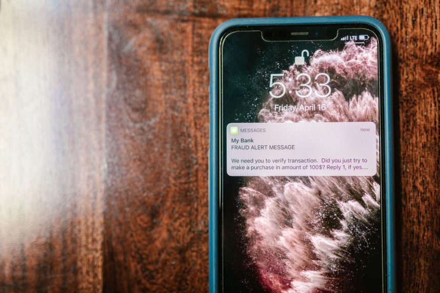 Celular exibindo um alerta de fraude sobre uma superfície de madeira.